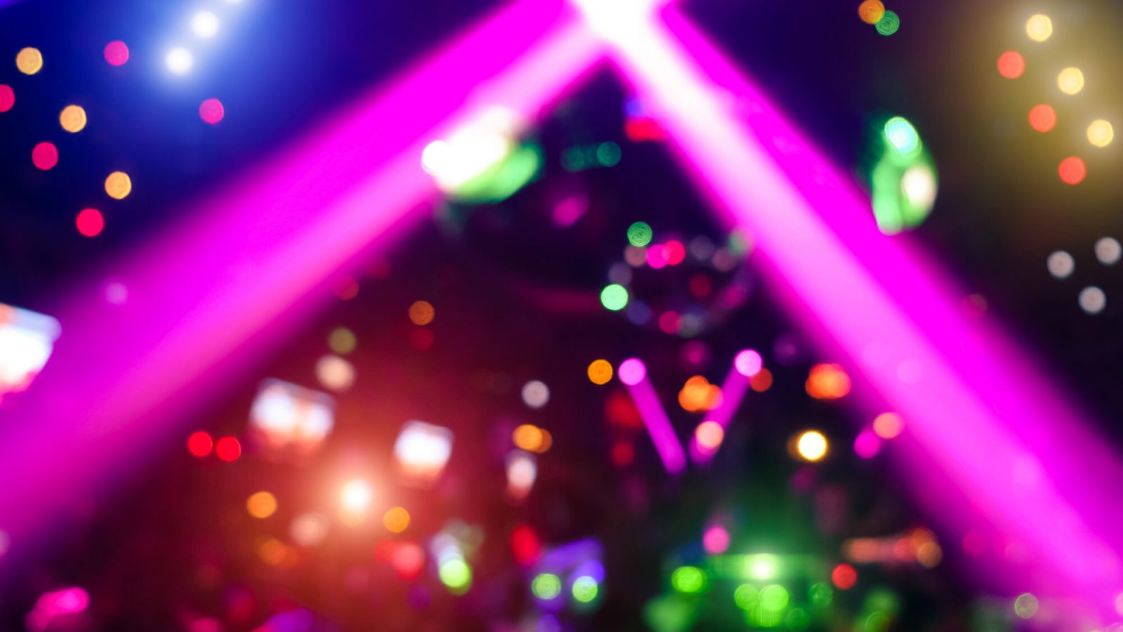 Abstract background with defocused bokeh of laser show in modern disco party night club - Concept of nightlife with music and entertainment - Image with powered colored halos and vivid bright lights